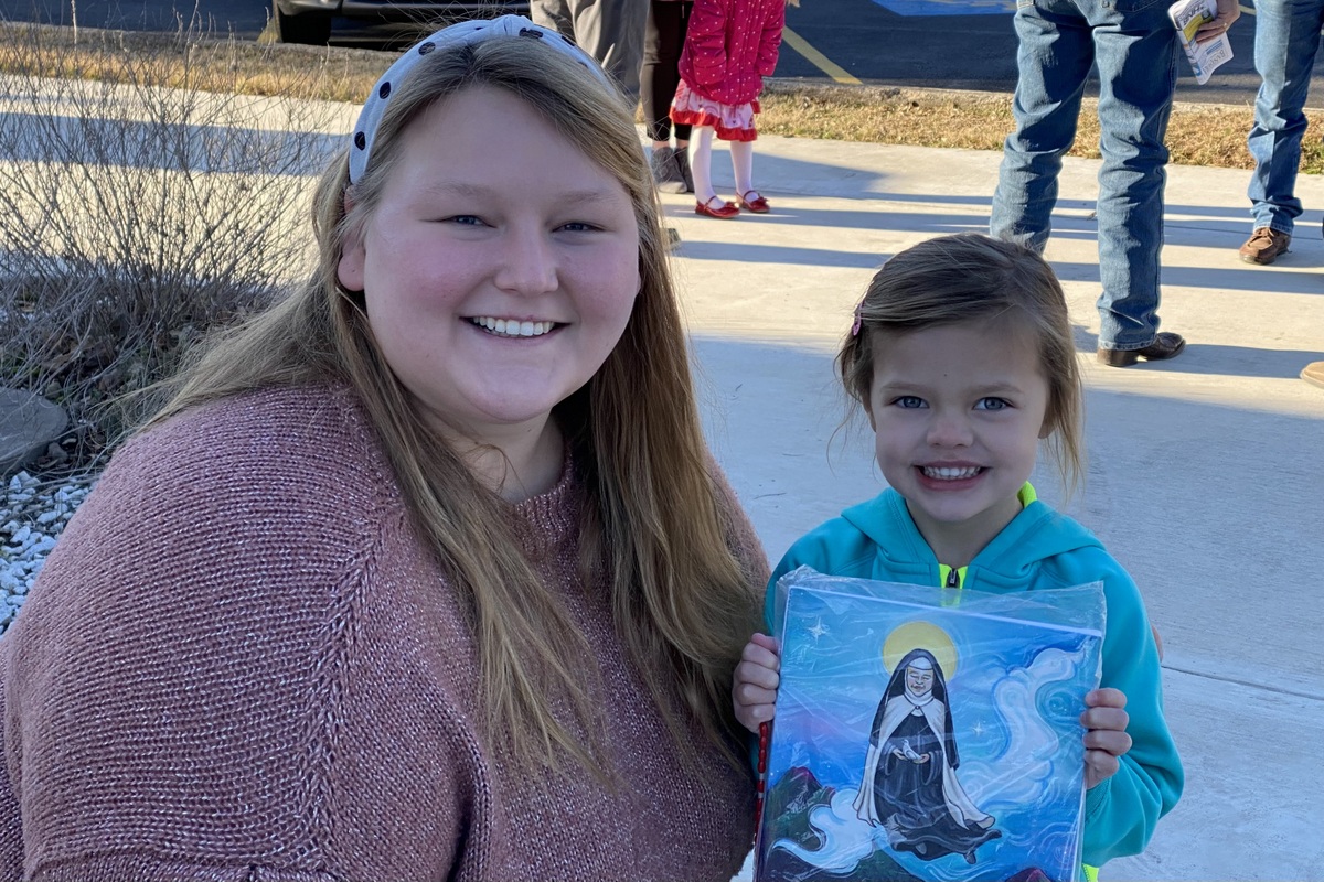 Lartista Emily Frost con la piccola Eleanor davanti alla chiesa parrocchiale in Texas dopo la Messa il giorno del dono del dipintojpg